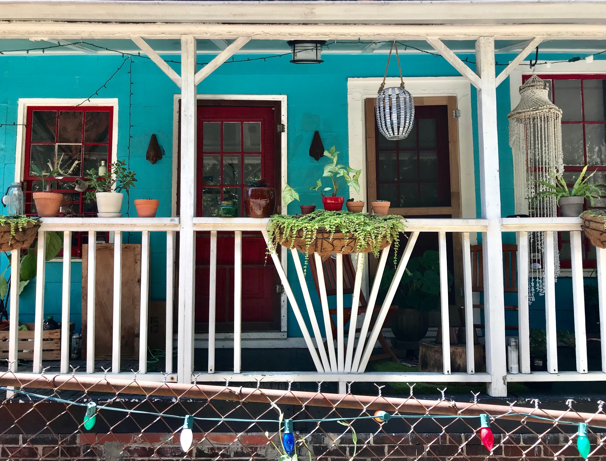 A green house with white railing on the front porch