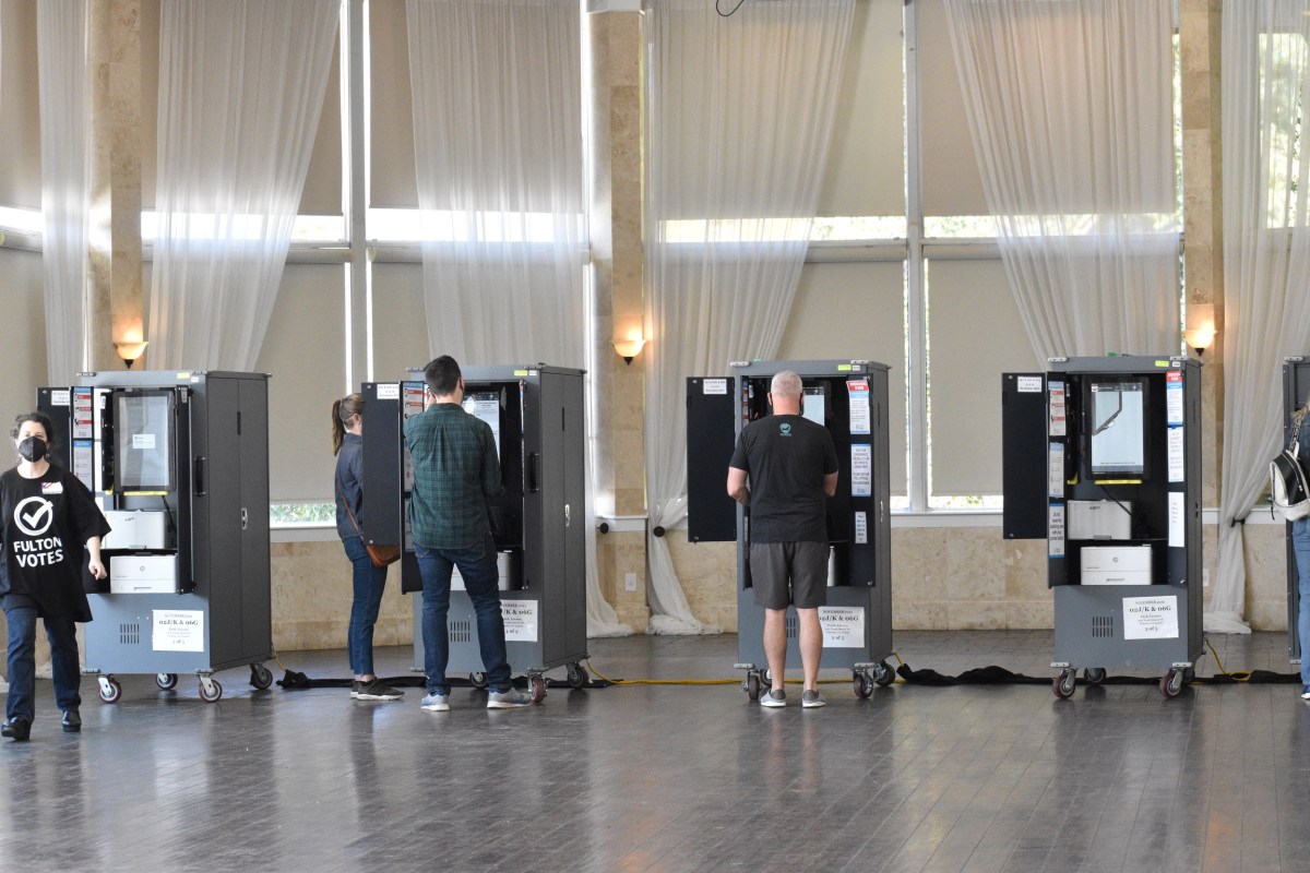 A line of voting booths and people voting at them.