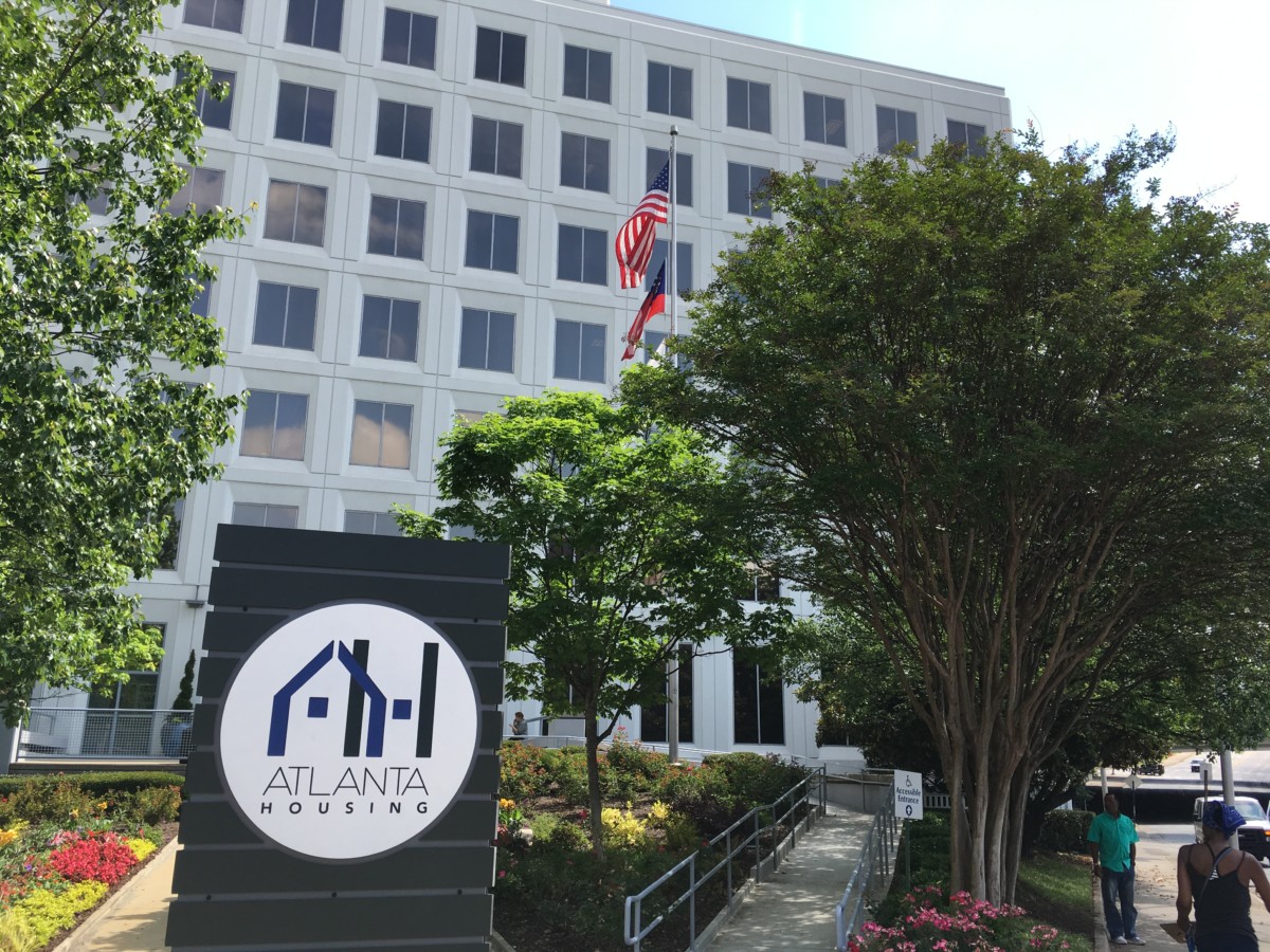 A sign with Atlanta Housing's logo stands in front of the agency headquarters, a blocky white building.