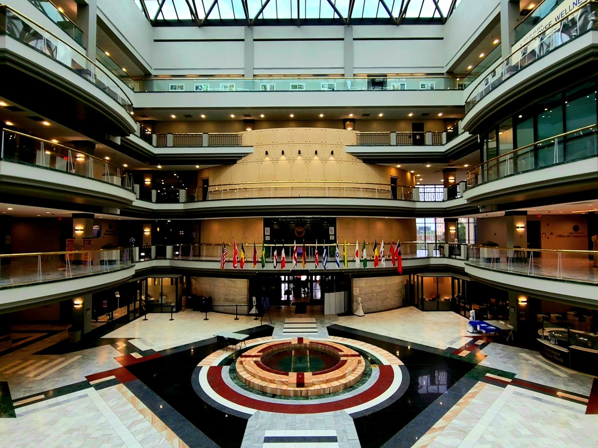 A vertical shot of the main atrium of Atlanta City Hall, which shows four tiered floors with a wraparound balcony overlooking the decent-sized, marble-floored rotunda.