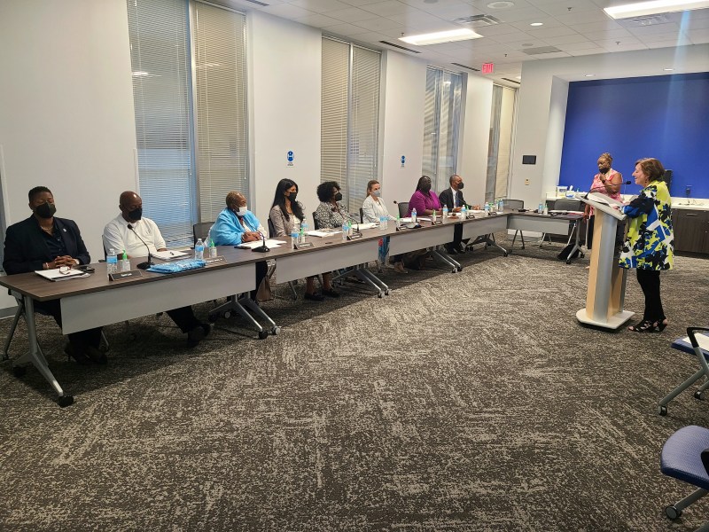 a woman speaks to a panel of housing authority commissioners