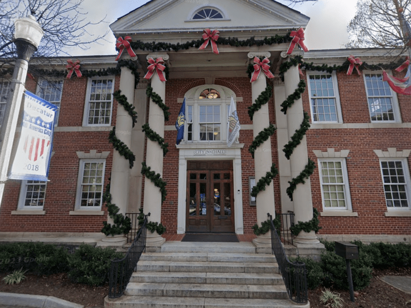 A red brick building with four, two-story columns wrapped in holiday décor.