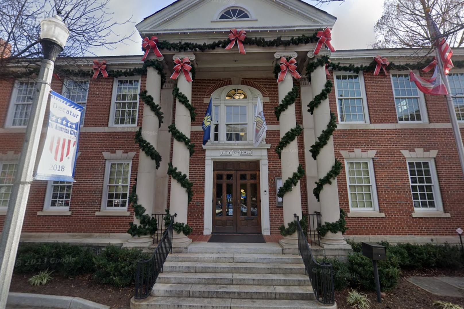 A red brick building with four, two-story columns wrapped in holiday décor.