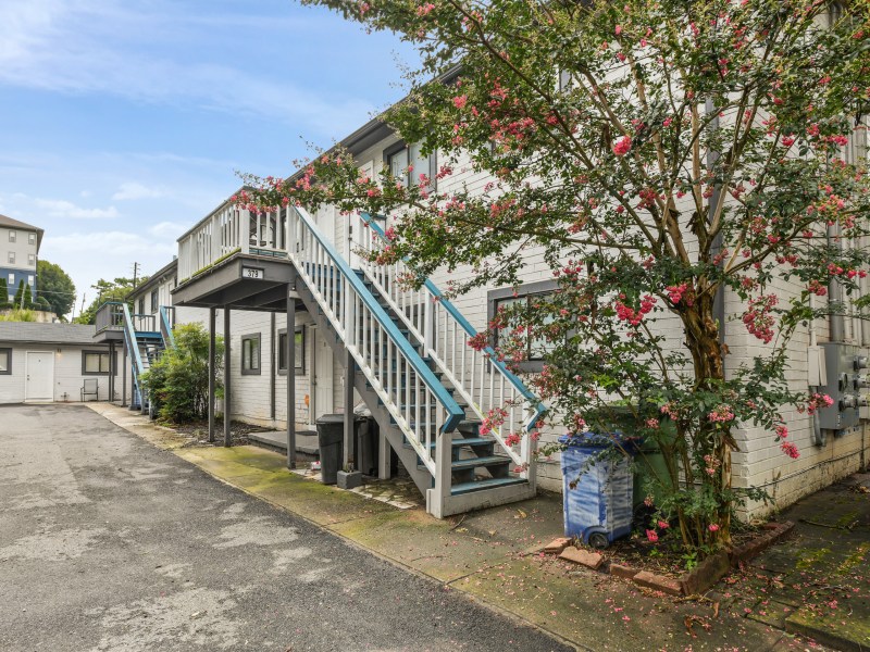 A photo of the Elm Street apartment complex, with a small tree out front and blue staircases.