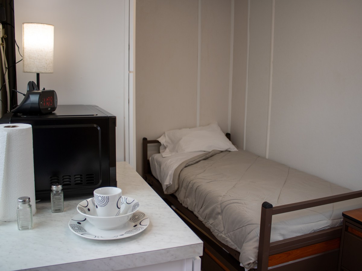 A photo of a small room at The Melody, with a twin bed and small kitchenette.