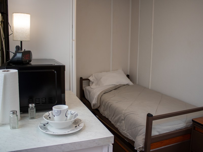 A photo of a small room at The Melody, with a twin bed and small kitchenette.