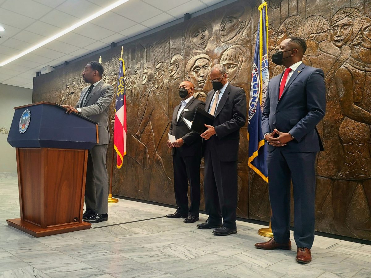 A photo of Mayor Andre Dickens at a podium, with former Atlanta Housing CEO Eugene Jones, Integral Group CEO Egbert Perry, and mayoral advisor Courtney English behind him.