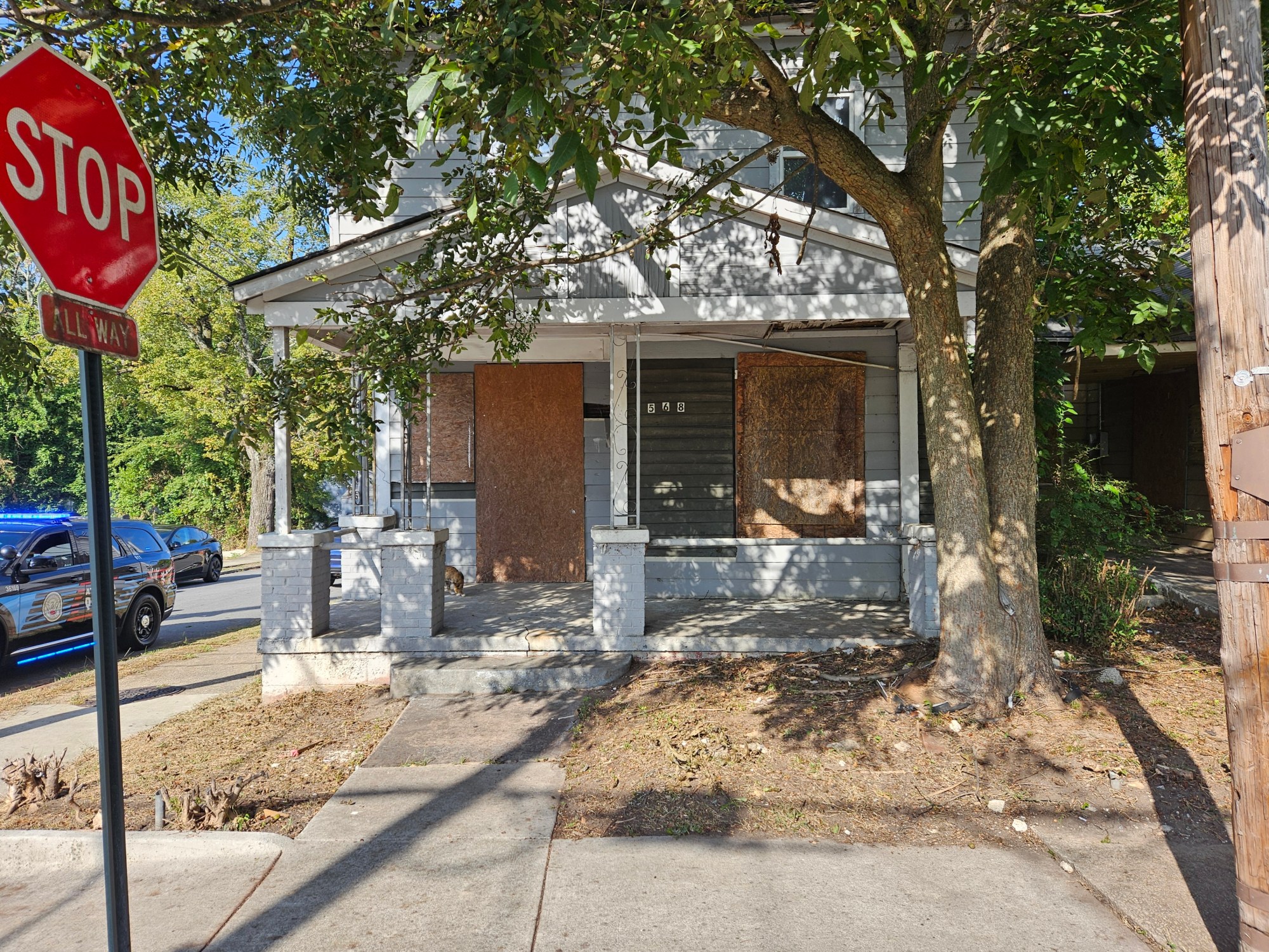 A photo of a boarded-up house with weeds sprouting around it.