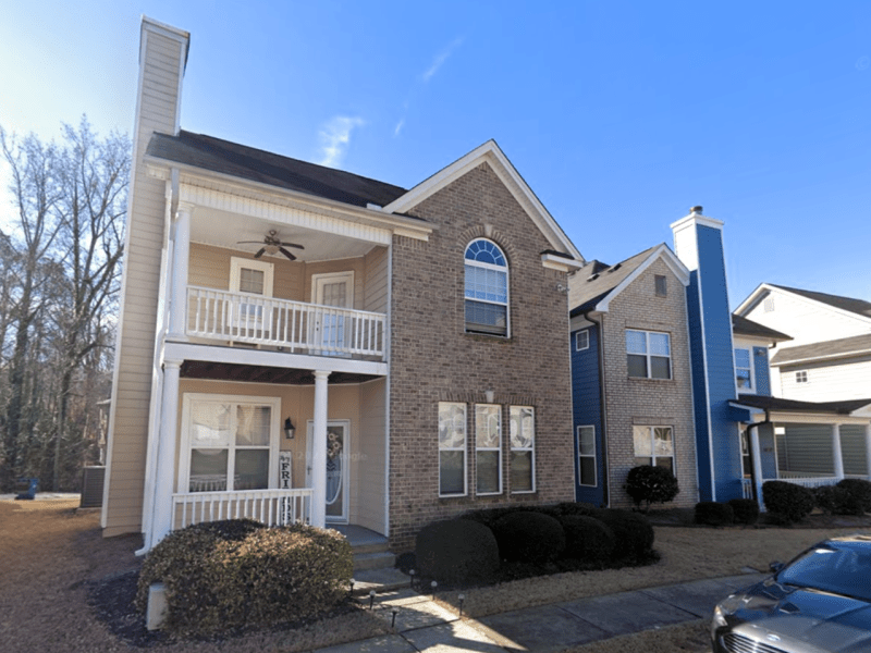 A photo of a two-story home with grey bricks and a multi-level patio.