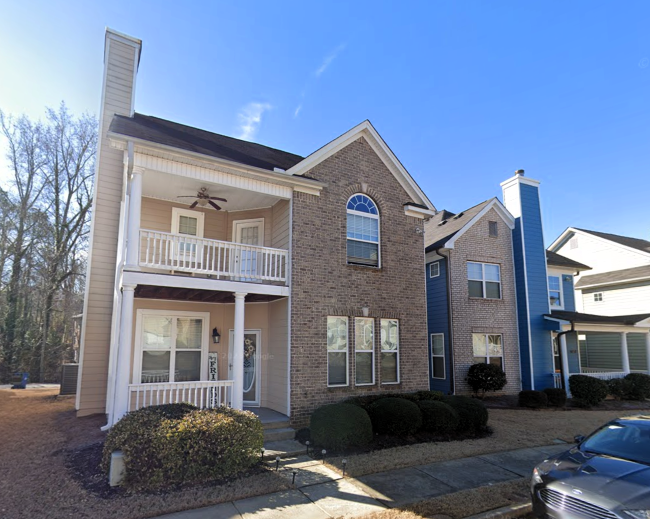 A photo of a two-story home with grey bricks and a multi-level patio.