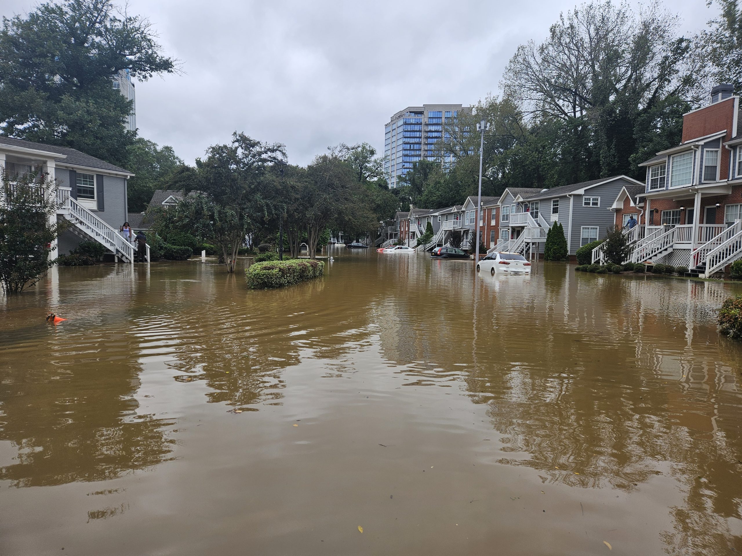 A photo of murky brown water flooding a low-rise apartment complex.