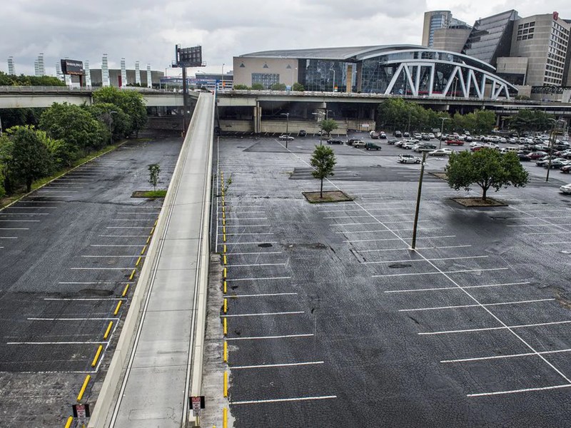 A photo of a rain-soaked parking lot, bisected by a ramp that leads to an overhead bridge.