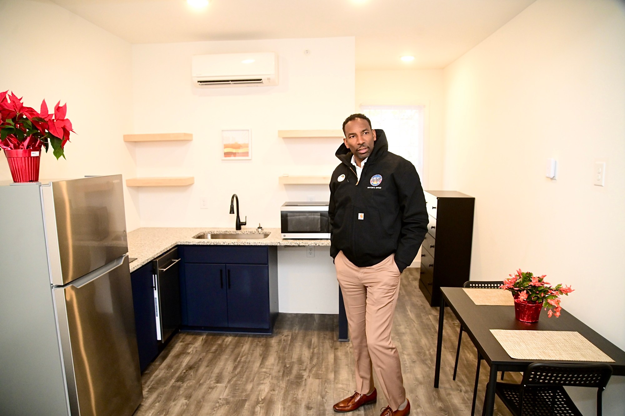 A photo of Atlanta Mayor Andre Dickens standing in a small apartment unit's kitchen.