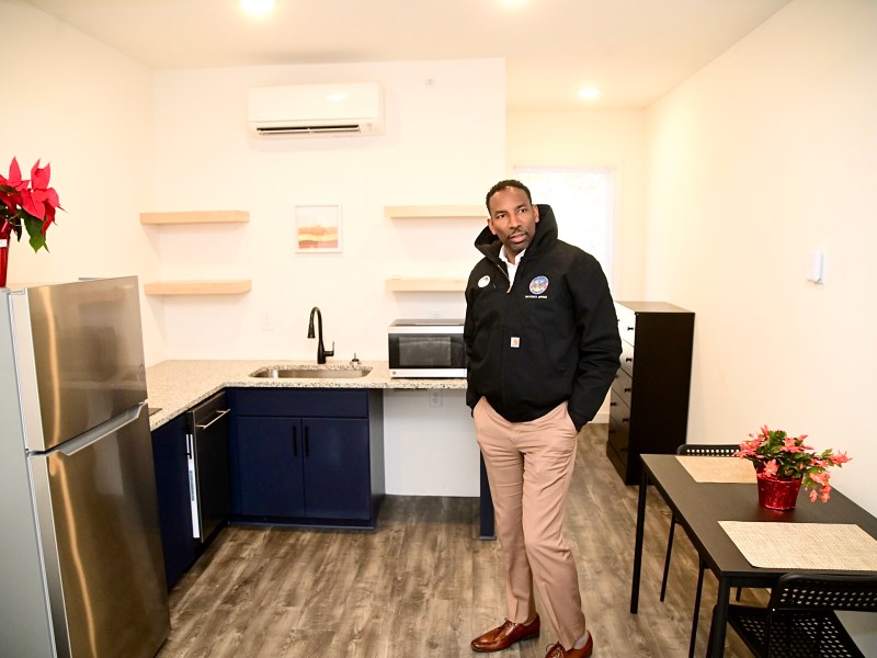 A photo of Atlanta Mayor Andre Dickens standing in a small apartment unit's kitchen.