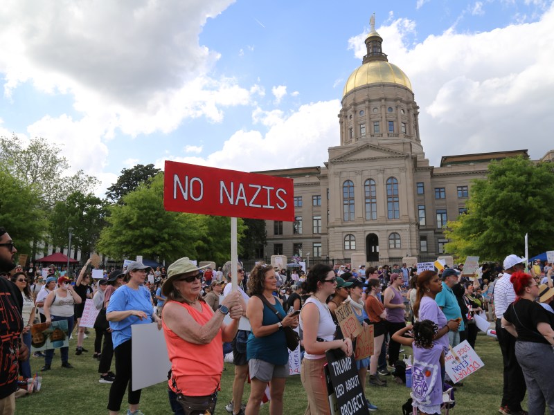 A woman holds a "NO NAZIS" sign in a crowd of demonstrators in front of the Gold Dome in Atlanta, GA.