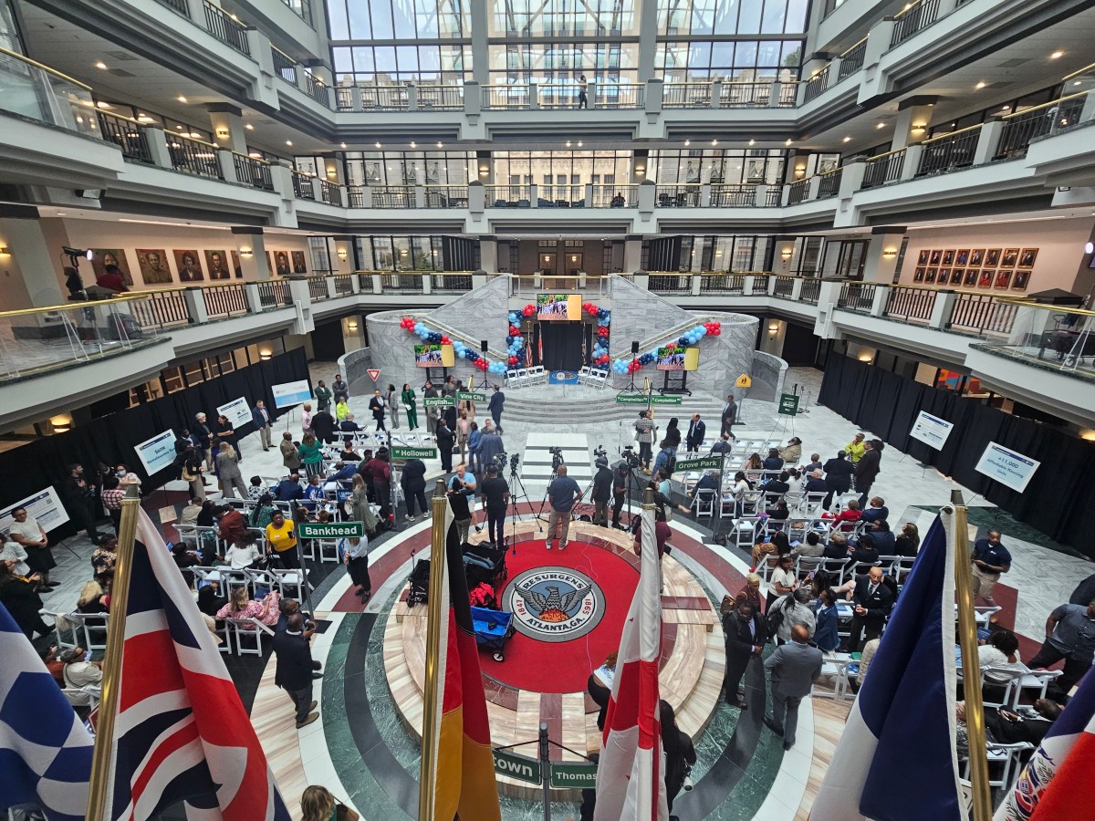 A photo of the atrium at Atlanta City Hall, decorated for a big announcement and brimming with people.